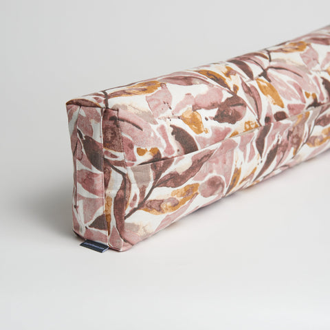 Floral patterned cylindrical pillow on a light gray background